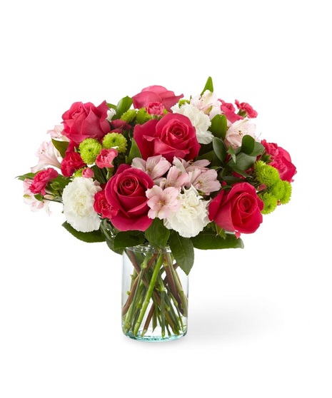 Bright pink roses, pink alstroemeria, white carnations and green mums in a clear glass vase
