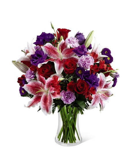 Stargazer lilies, red roses & more in a clear glass vase
