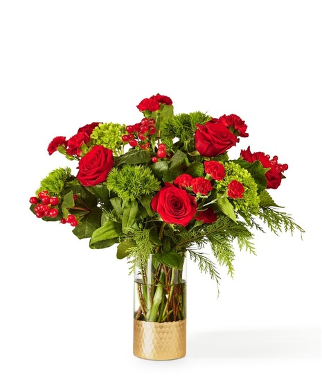 red flowers in tall cylinder vase that is trimmer with gold
