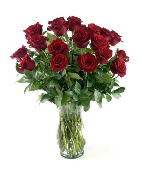 Two dozen red roses and greenery presented in a clear glass vase