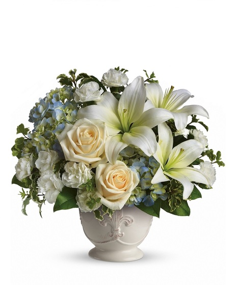 Funeral arrangement of white flowers and greenery in an elegant basket.