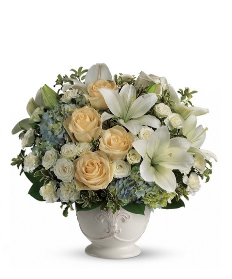 Funeral arrangement of white flowers and greenery in an elegant basket.