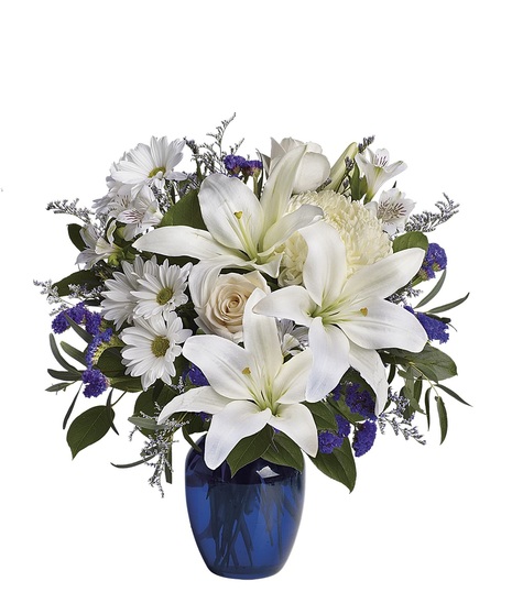 White roses and lilies in a sapphire blue cube vase.