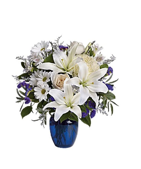 White roses and lilies in a sapphire blue cube vase.