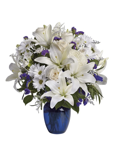 White roses and lilies in a sapphire blue cube vase.