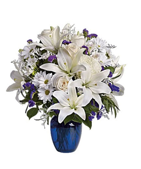 White roses and lilies in a sapphire blue cube vase.