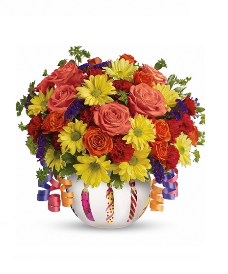 Birthday gift of bright flowers in a frosted glass bowl adorned with a shiny birthday candle motif, and ribbons. 