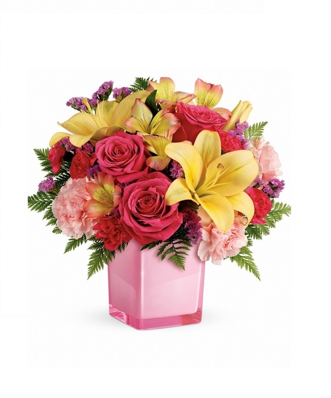 Pink cube vase filled with lilies, roses, carnations and more