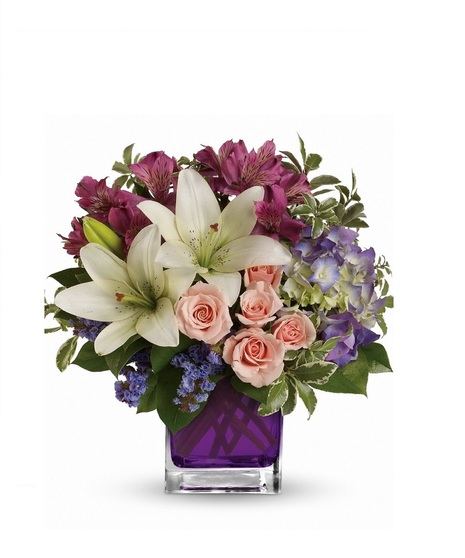 Hydrangea, spray roses, asiatic lilies and more arranged in a vibrant violet glass cube