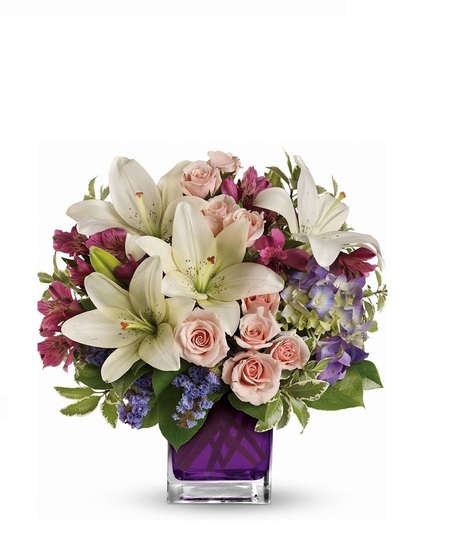 Hydrangea, spray roses, asiatic lilies and more arranged in a vibrant violet glass cube