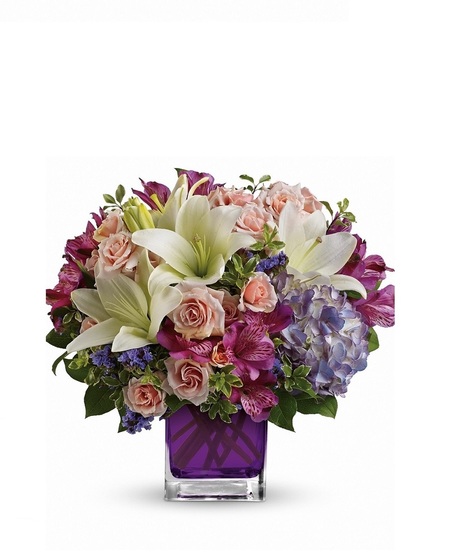 Hydrangea, spray roses, asiatic lilies and more arranged in a vibrant violet glass cube