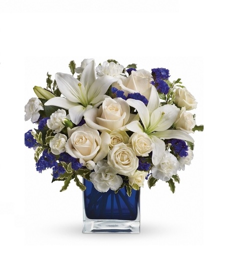 White roses and lilies in a sapphire blue cube vase.