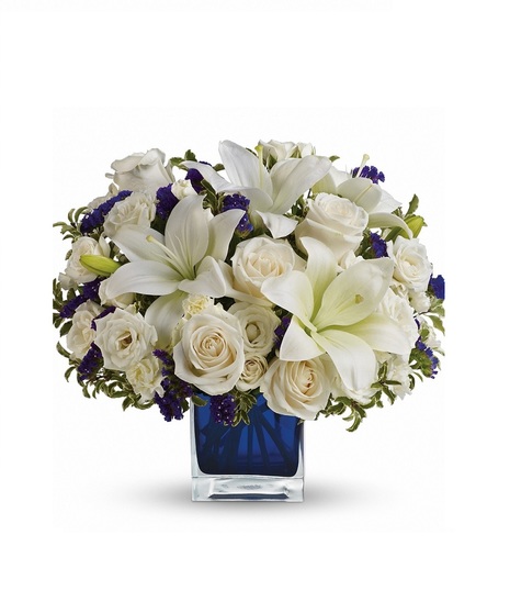 White roses and lilies in a sapphire blue cube vase.