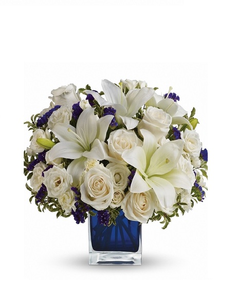 White roses and lilies in a sapphire blue cube vase.